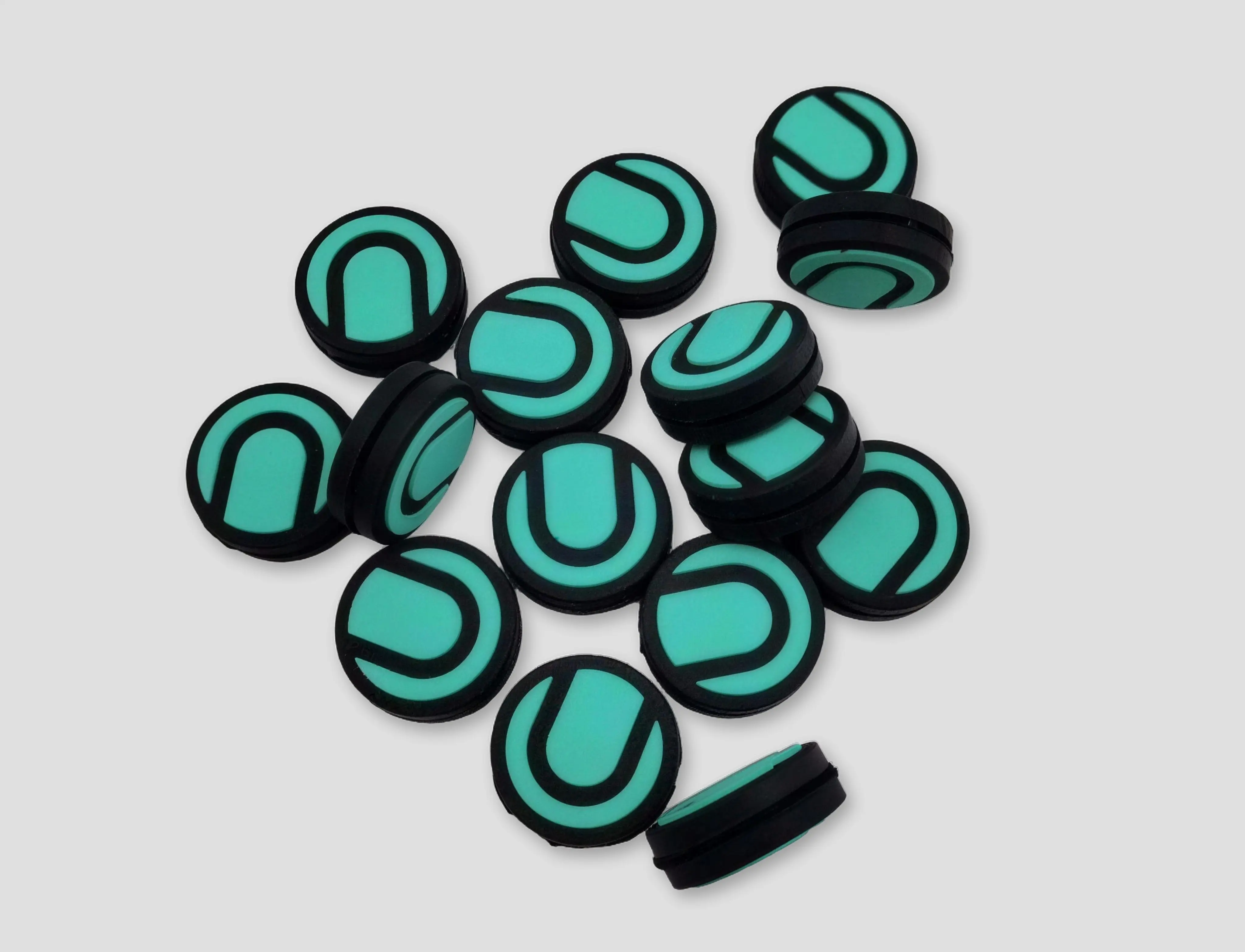 A finished pile of teal and black custom tennis dampeners with clean color separation