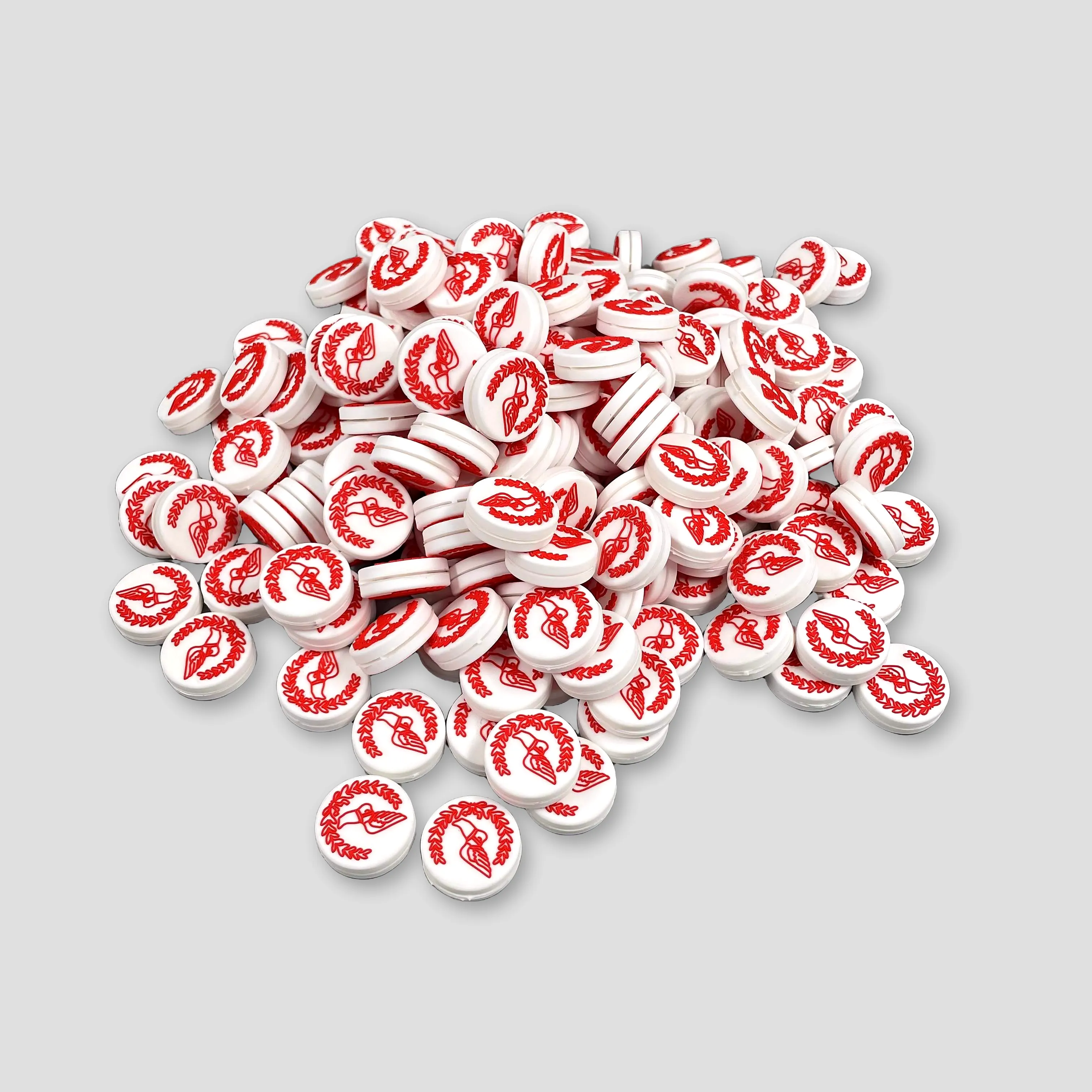 A production-scale pile of white custom tennis dampeners with sharp red raised artwork