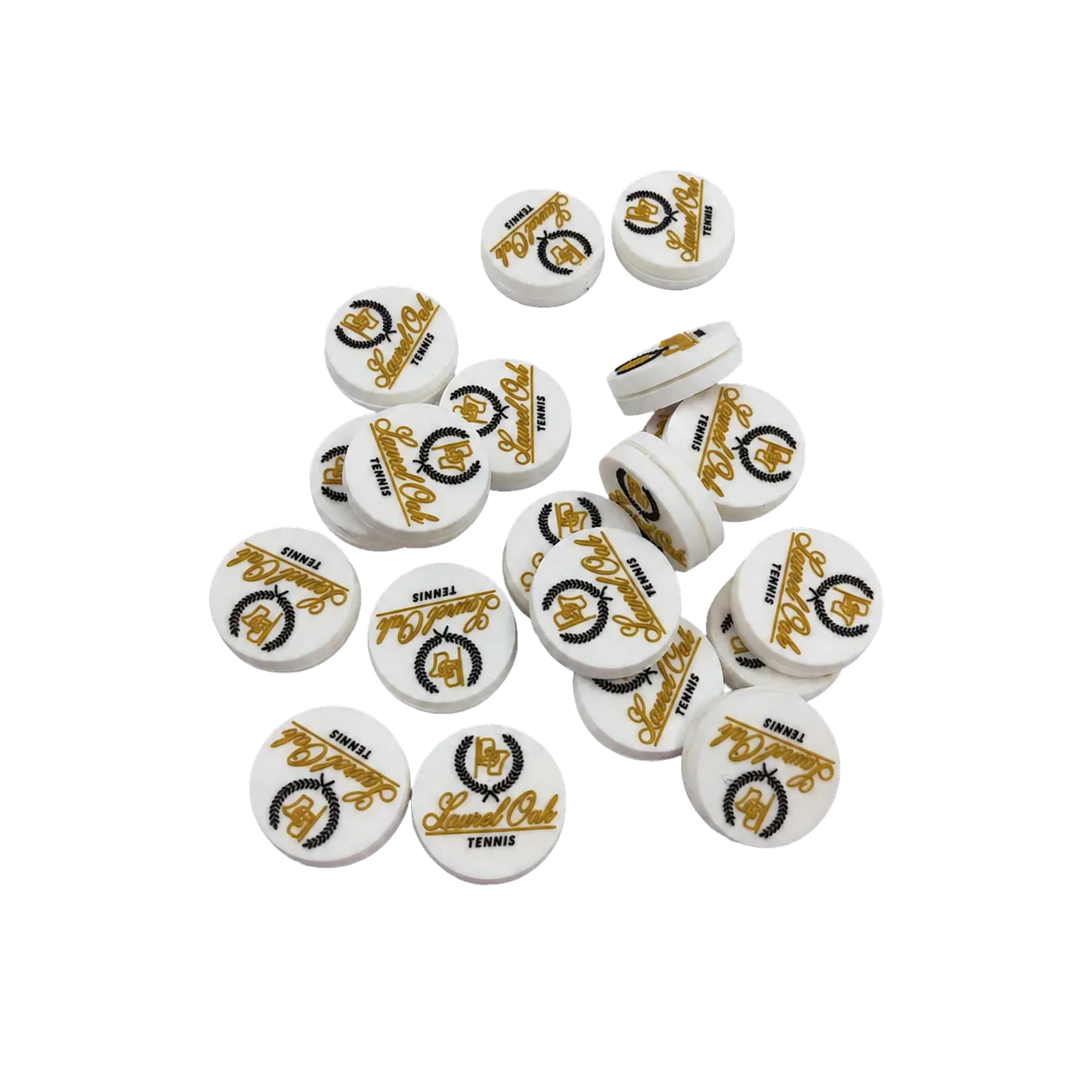 A production group of white, gold, and black Laurel Oak Tennis custom dampeners on a gray surface